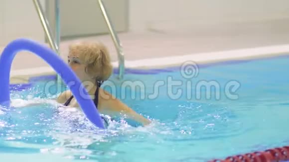 老妇人在游泳池里用面条做运动视频的预览图