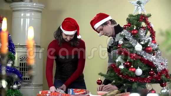 一对夫妇在树旁打包圣诞礼物视频的预览图