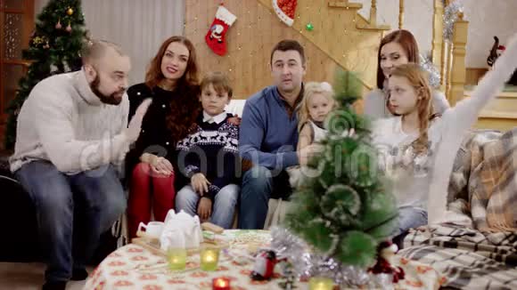 圣诞晚会上幸福的家庭在镜头前看着挥手视频的预览图