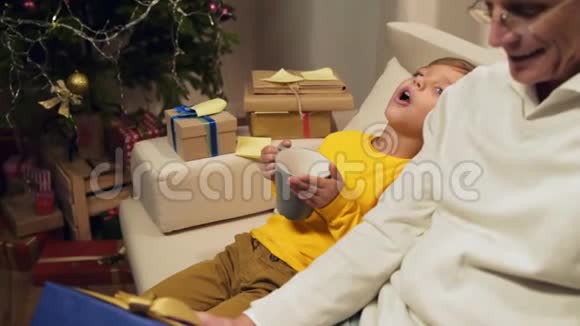 快乐的小男孩和他的祖父一起躺在沙发上视频的预览图