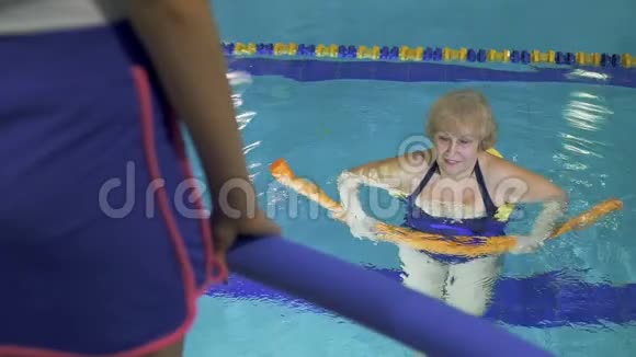 老年妇女在游泳池里用面条做健身运动视频的预览图