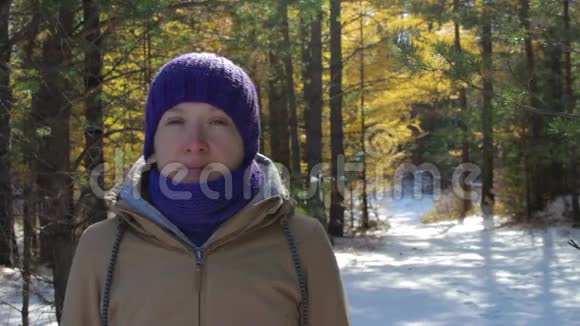 阳光明媚的一天一个年轻的女人在一个下雪的冬天森林里的肖像视频的预览图