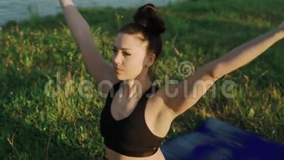 早上在湖边做瑜伽的女人日出时在莲花位置的美女视频的预览图