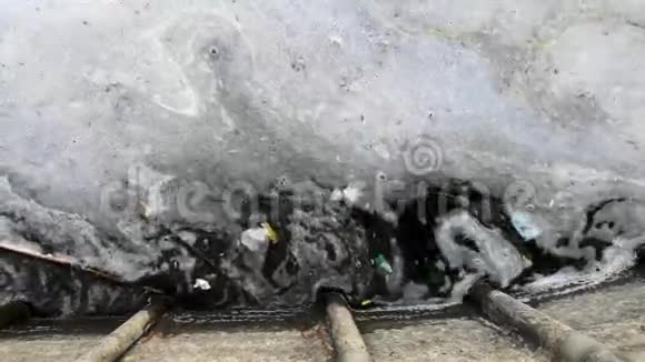 沙滩上的塑料瓶和眼镜脏水里有垃圾漂浮岸边的白色泡沫视频的预览图