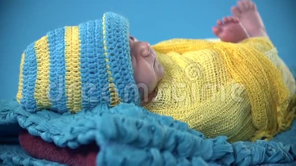 婴儿在彩色床单上的蓝色毯子上休息视频的预览图