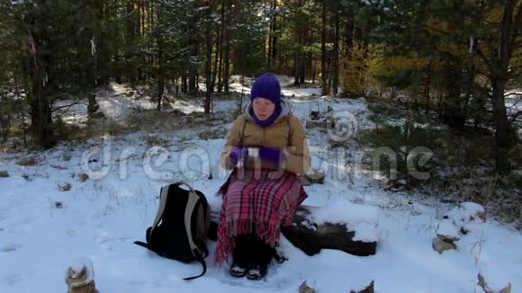 冬林中喝热茶或咖啡的年轻女子视频的预览图