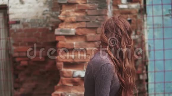 一个美丽的红发女孩的特写肖像头发在风中飘扬有神秘眼睛的女孩慢动作视频的预览图