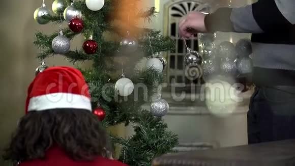 中镜头男女在圣诞树上挂装饰品视频的预览图