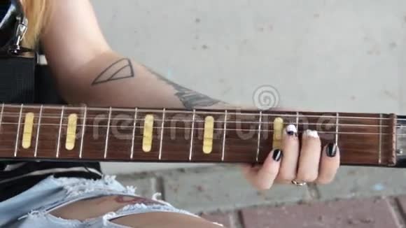 有纹身的女孩坐在涂鸦墙附近弹电吉他视频的预览图