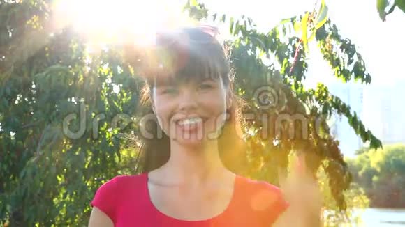 美丽的笑女在公园里竖起大拇指背景是阳光视频的预览图