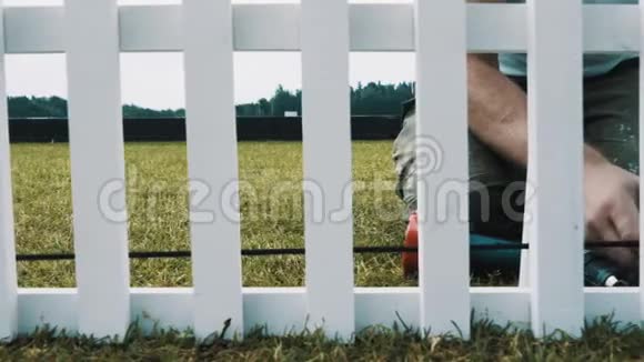 木工在绿草地上筑白色木制英语围栏视频的预览图