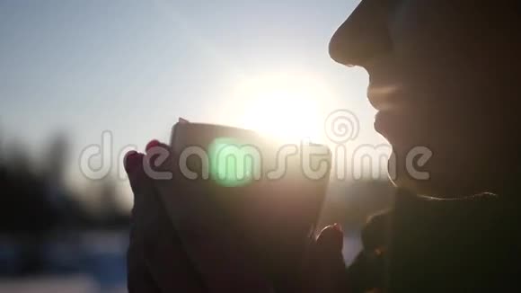 一个年轻的女孩站在街道上享受着一杯美味的热咖啡背景是美丽的冬日夕阳视频的预览图