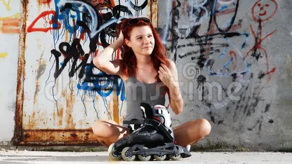 在涂鸦背景下穿着溜冰鞋的坐着女孩视频的预览图