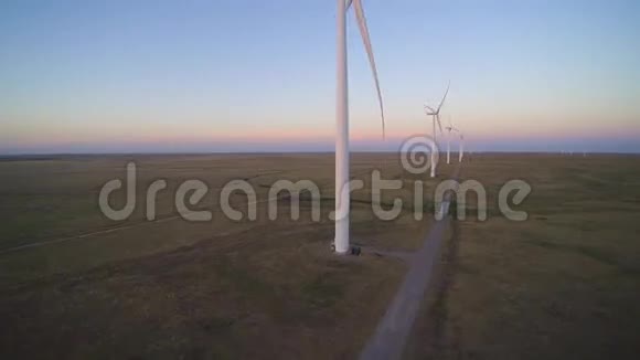 在美丽的黄昏夕阳下在大片田野上空中拍摄4k大白风电场视频的预览图