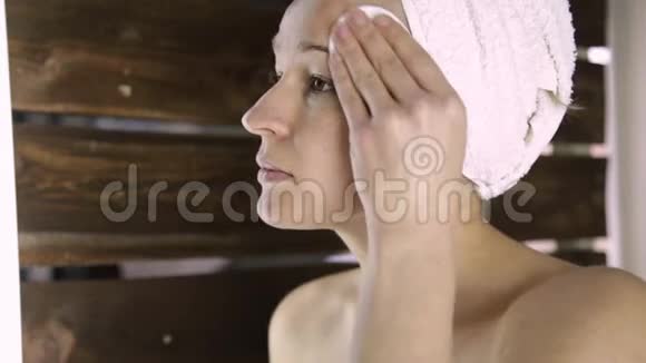 穿毛巾的漂亮女人在镜子前卸妆家庭水疗中心视频的预览图