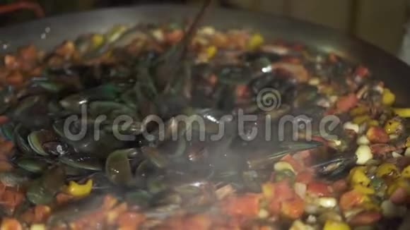 厨师烹饪海鲜贻贝和虾与蔬菜在海鲜饭锅关闭准备西班牙食物的过程视频的预览图
