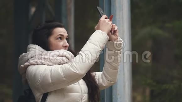 一位年轻的女游客在旅行时通过电话拍摄自己和乡村的照片视频的预览图