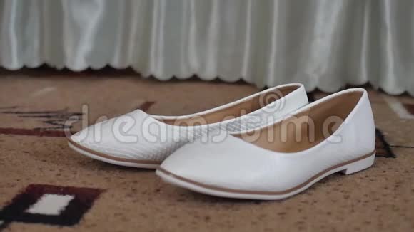 白色芭蕾舞平底鞋带米色包站在床旁边的卧室地板上视频的预览图