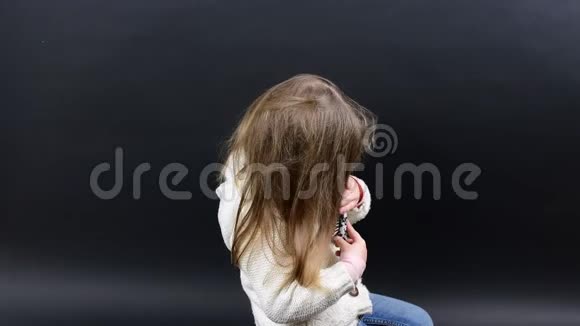 可爱的女孩梳头小女孩穿着冬天的衣服可爱的黑背景小女孩视频的预览图