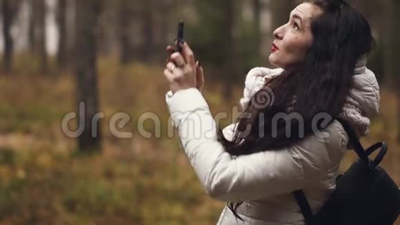 一位年轻的女游客在旅行时通过电话拍摄自己和乡村的照片视频的预览图