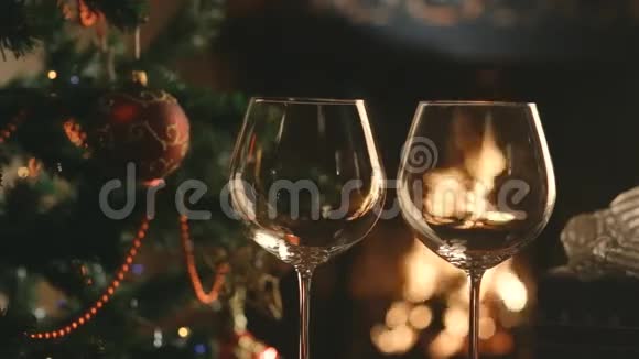 把葡萄酒倒入圣诞树和壁炉背景上的玻璃杯中视频的预览图