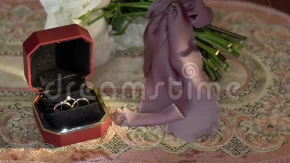 三枚结婚戒指放在一个红盒子里还有新娘的花束视频的预览图