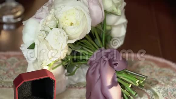 三枚结婚戒指放在一个红盒子里还有新娘的花束视频的预览图