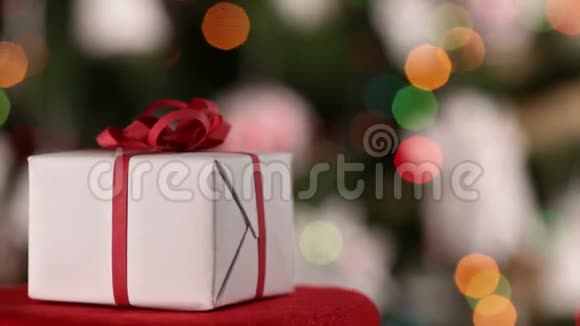 圣诞礼物在圣诞树上闪烁的灯光前旋转视频的预览图