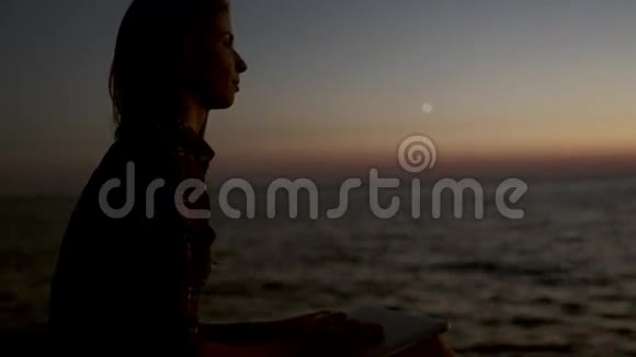 坐在海滩上的女孩手提电脑紧闭视频的预览图