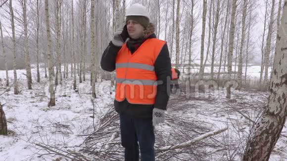 伐木工人在树枝旁的桦树林里用智能电话交谈视频的预览图