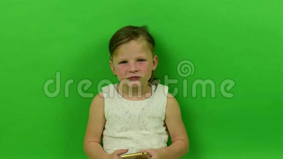 可爱的小女孩在色度键背景上使用手机穿着浪漫裙子的小女孩白色婚纱礼服视频的预览图