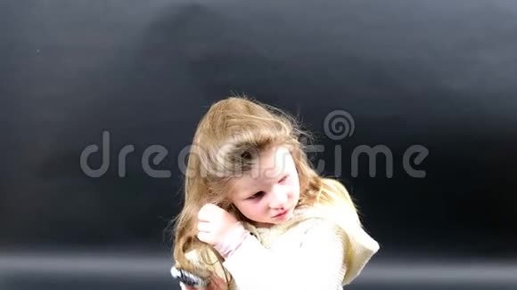 可爱的女孩梳头小女孩穿着冬天的衣服可爱的黑背景小女孩视频的预览图