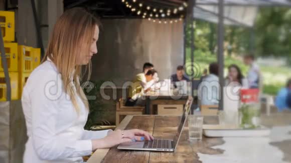 年轻漂亮的商务女性在户外咖啡厅午休时使用笔记本电脑视频的预览图