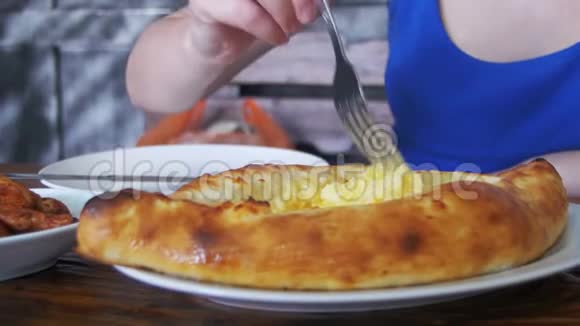 女人吃阿贾里人Khachapuri与叉子在格鲁吉亚餐厅的木制桌子格鲁吉亚粮食视频的预览图