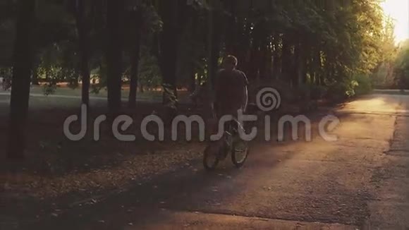 穿着自由风格的人骑在公园里骑着一辆自行车BMX上的高大树木视频的预览图