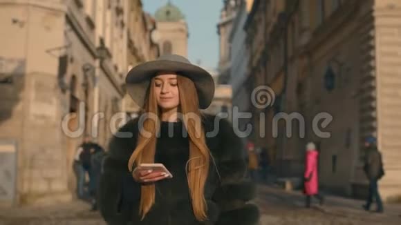 戴着灰色帽子和长发的年轻女子通过智能手机进行交流视频的预览图