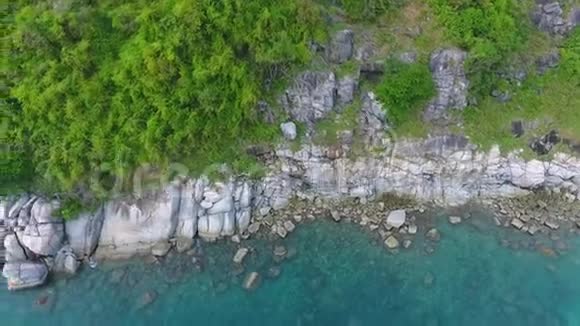 海岸蓝色海水中有大石头岩石上有绿色的手掌高清鸟瞰图泰国普吉岛视频的预览图