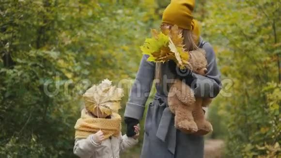 小女儿和妈妈一起在秋天公园散步玩耍躲在树叶后面视频的预览图