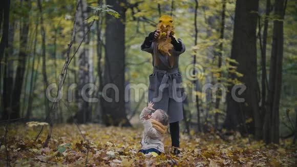 幸福的家庭观念小女儿和妈妈在秋天公园玩黄叶慢动作视频的预览图