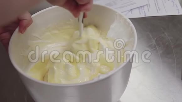 将蛋黄和鲜奶油用刮刀拌入碗中视频的预览图