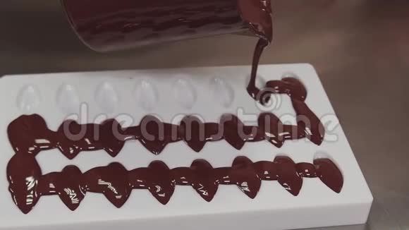 糕点厨师把融化的巧克力倒入白色塑料模具视频的预览图