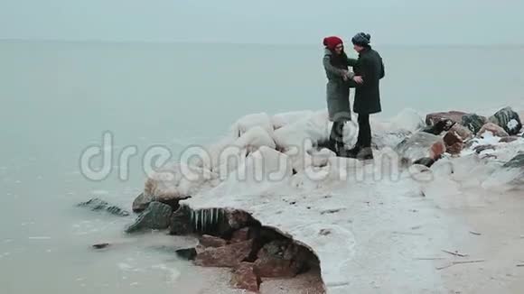 年轻的一对夫妇站在冬天的海边视频的预览图