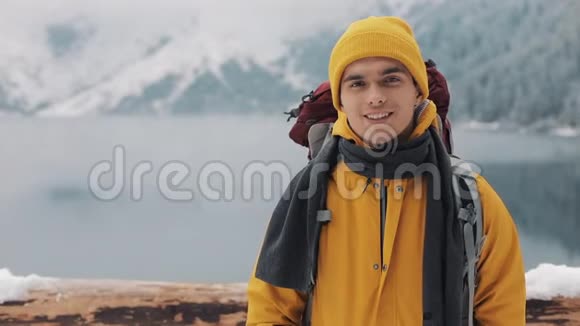 穿着冬装的年轻迷人男子的肖像穿着黄色冬装的徒步旅行者看着摄像机视频的预览图