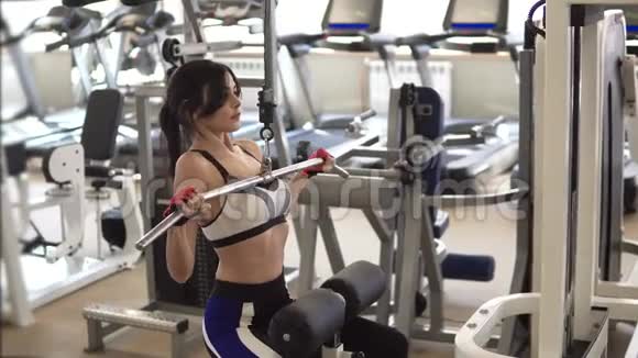 有魅力的女运动员在健身房的训练器械上做运动在肌肉上做运动的女孩视频的预览图
