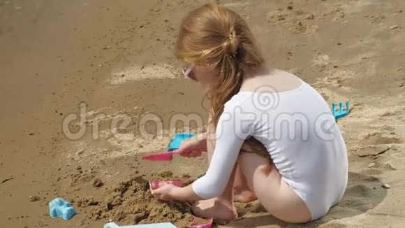 女孩在海滩上玩沙子用模子雕像夏日阳光明媚假期视频的预览图