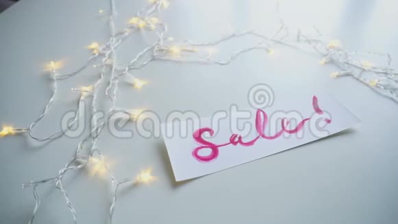 水彩铭文出售在白纸上桌子上有闪烁的花环在工作室视频的预览图