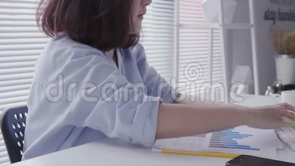 美丽的年轻拉斯特亚裔妇女在家里坐在客厅里用笔记本电脑工作视频的预览图