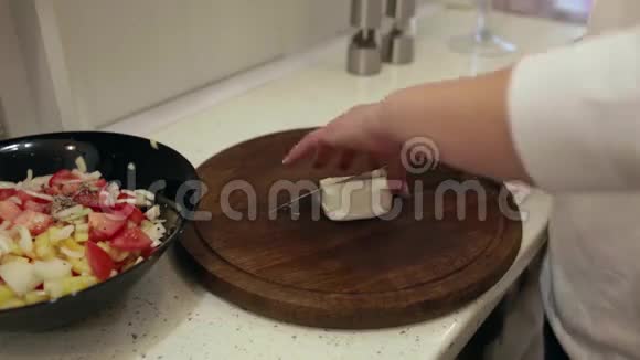 厨房里的一个年轻女人在准备沙拉切奶酪视频的预览图