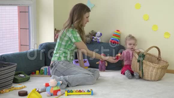 快乐的母亲和可爱的蹒跚学步的女儿女孩把玩具放在篮子里视频的预览图