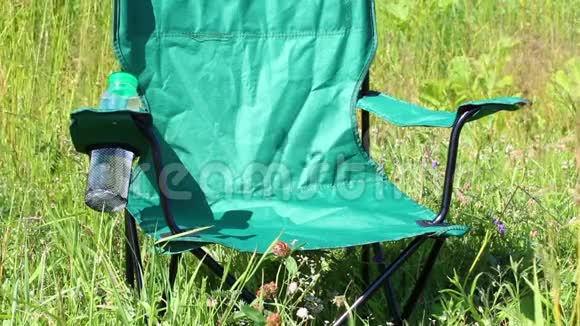 一张野餐椅矗立在一片轻浮的草地上草本植物和花朵从夏风中摇摆视频的预览图